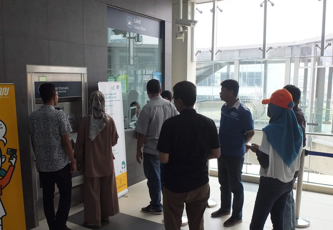 Group of 5 people queueing in locket while no one use the ticketing machine next to it